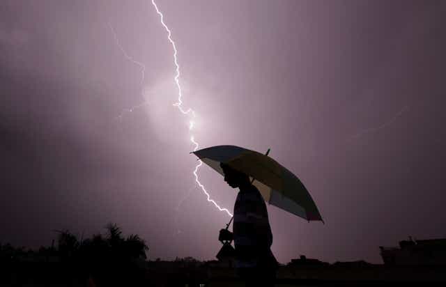 <p>Representative: A pedestrian walks with an umbrella as lightning strikes during an evening thunderstorm in Jammu on 14 May 2015</p>