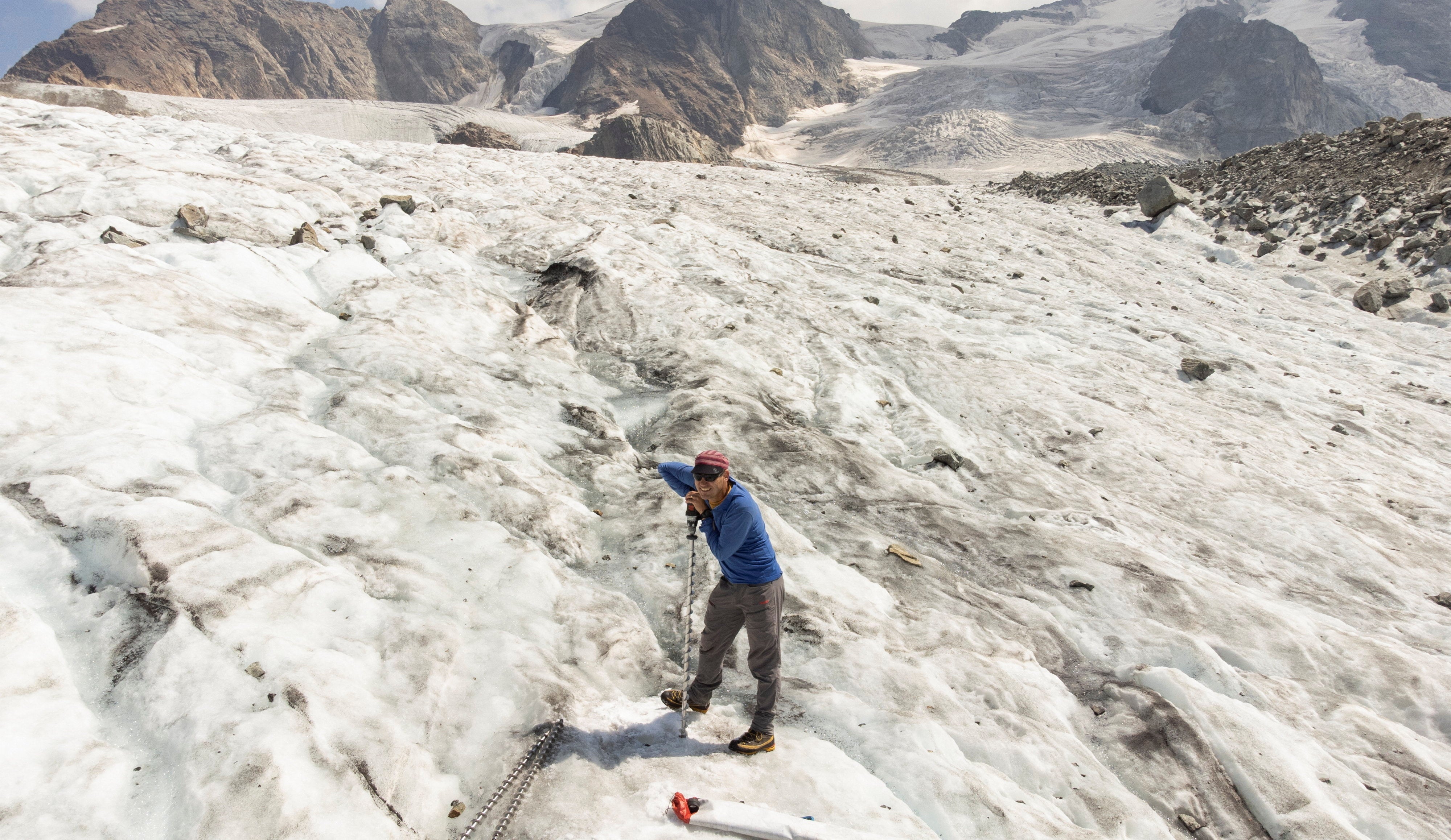 A glaciologist drills a hole at a measuring point on the Pers Glacier near the Alpine resort of Pontresina, Switzerland