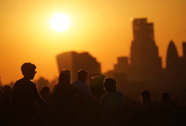 People in Greenwich Park watch the sun set over London in July 2021 (Yui Mok/PA)