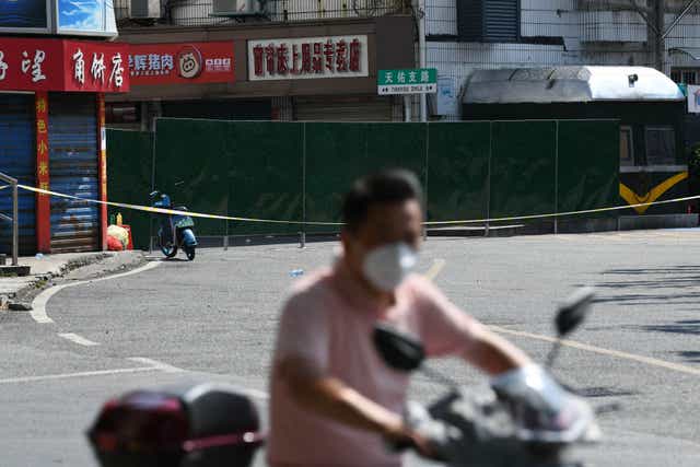 <p>A resident rides a scooter past a blocked street amid the Covid-19 coronavirus pandemic in Nanchang, in China’s central Jiangxi province on 22 July</p>