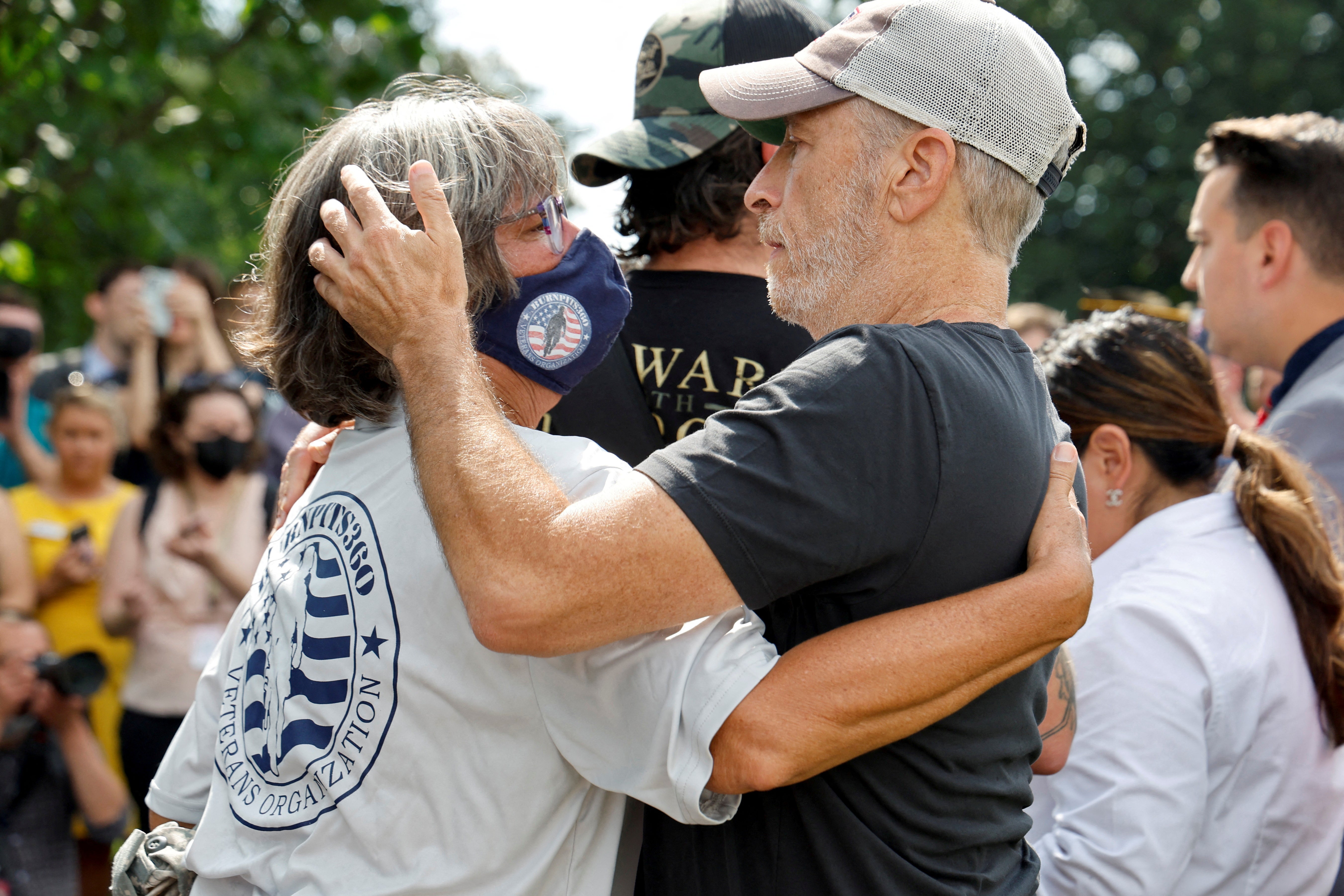 Comedian Jon Stewart hugs Susan Zeier at the press conference on 28 July