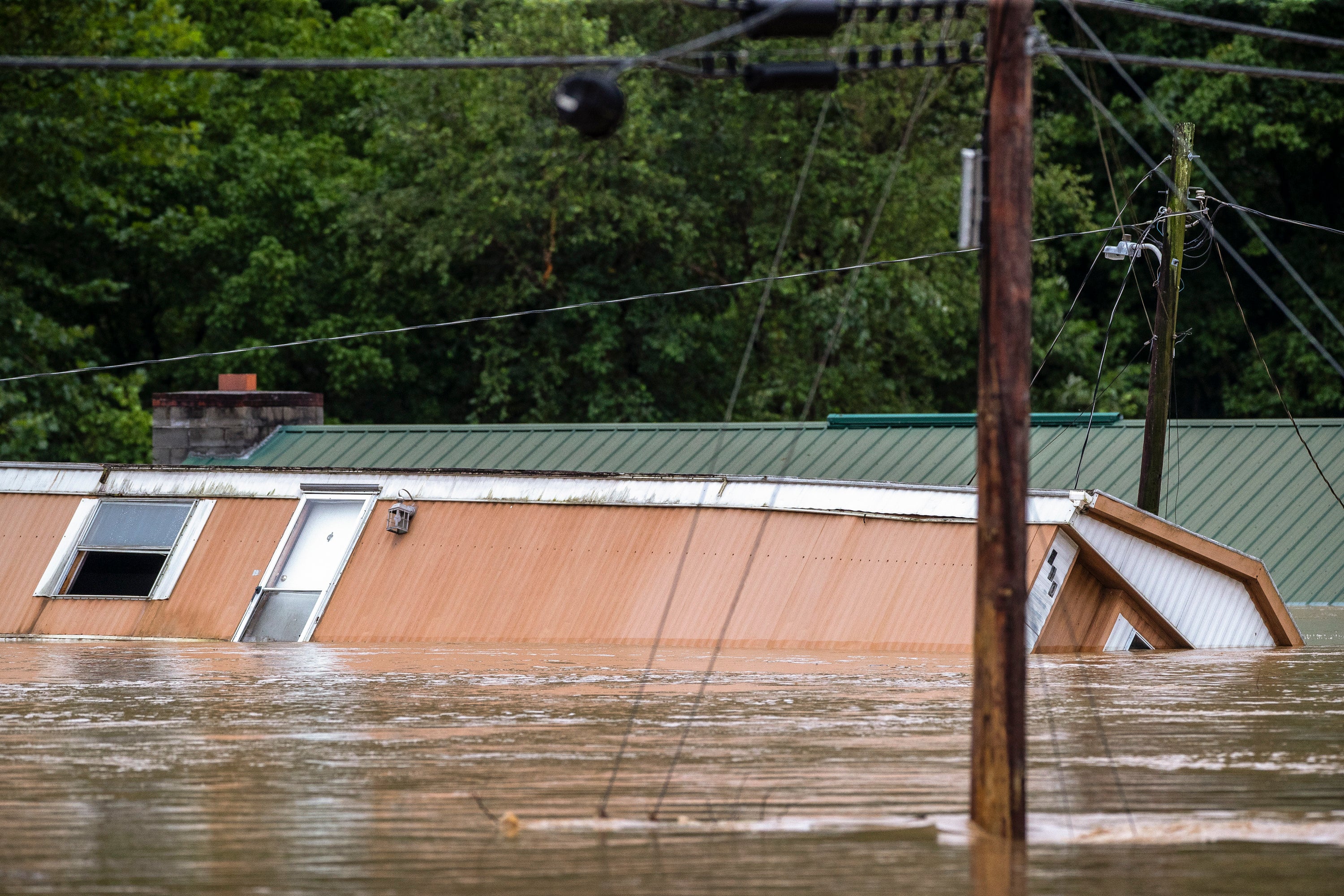 A home tips in floodwaters in Lost Creek, Kentucky on Thursday