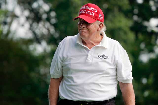 <p>Former President Donald Trump reacts to his tee shot</p>