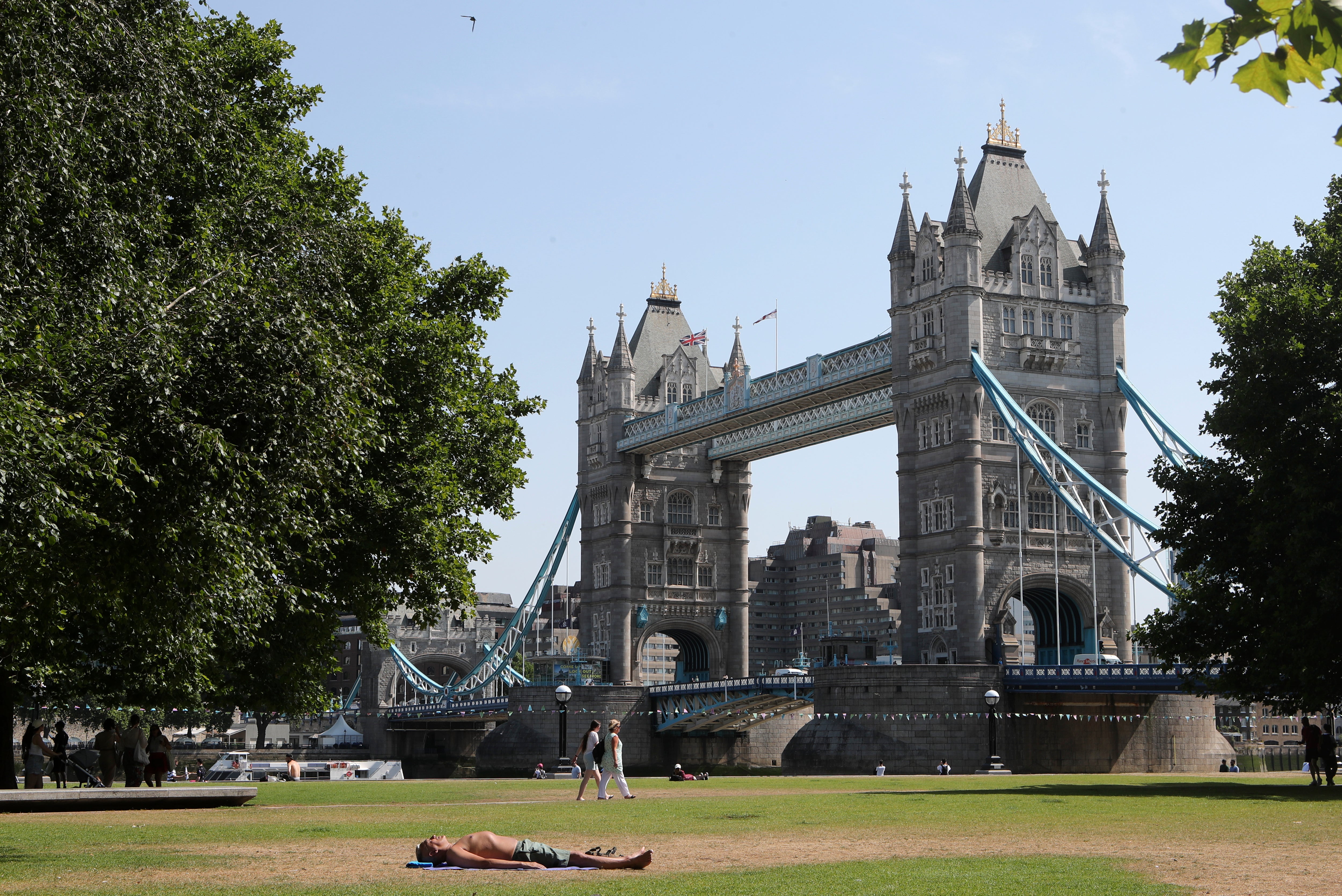 A man sunbathes near Tower Bridge during the prolonged record-breaking heatwave
