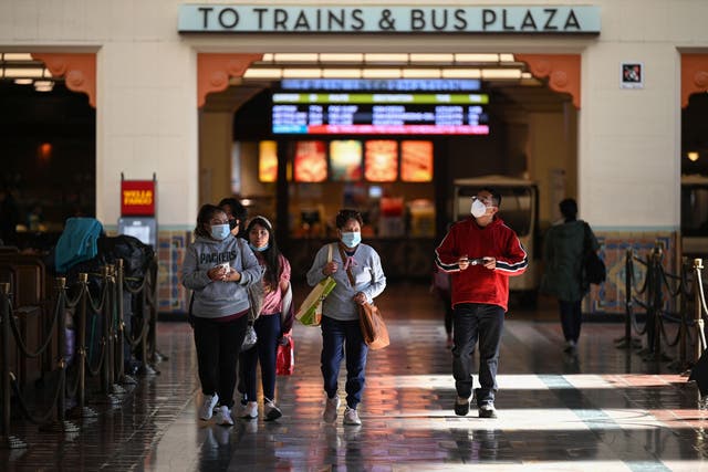 <p>A family wearing face masks walks through Union Station in Los Angeles, California, January 5, 2022. </p>