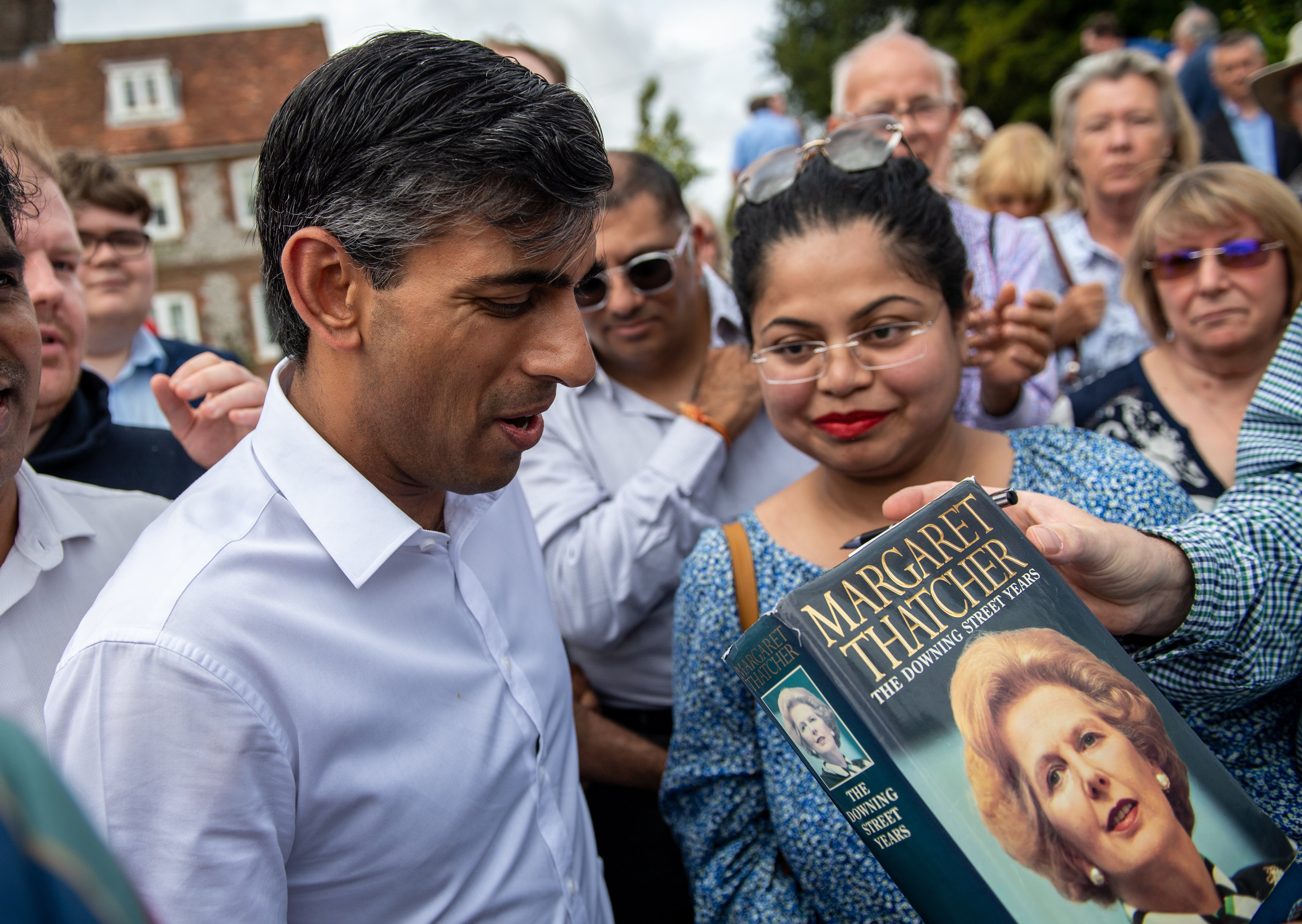 Rishi Sunak is handed a copy of former prime minister Margaret Thatcher’s book to sign at an event at Manor Farm, in Ropley near Winchester, Hampshire (Chris J Ratcliffe/PA)