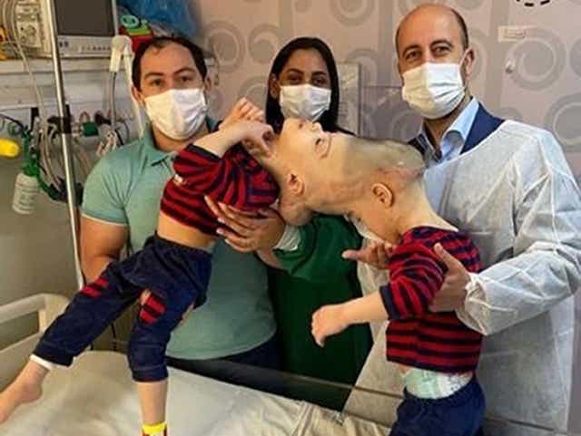 <p>UK-based surgeon Noor ul Owase Jeelani with Bernardo (left) and Arthur, and parents Adriely and Antonia Lima</p>