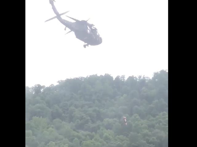 <p>The 83-year-old woman is just visible being hoisted into the Black Hawk helicopter</p>