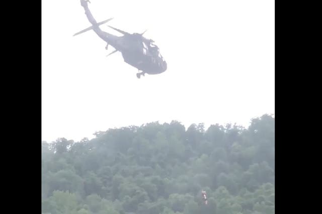 <p>The 83-year-old woman is just visible being hoisted into the Black Hawk helicopter</p>