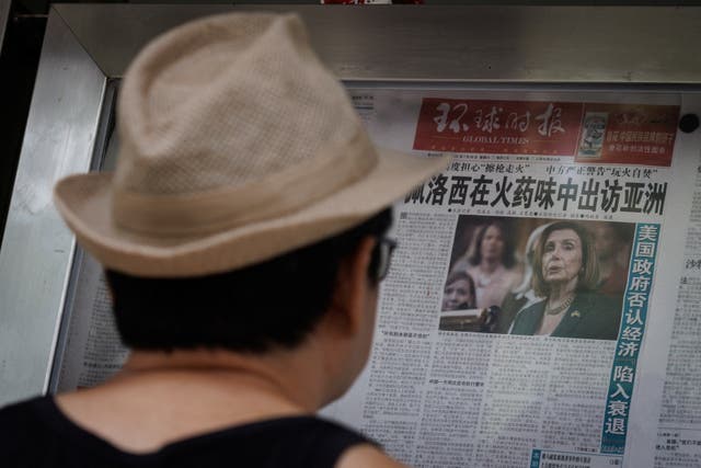 Un hombre lee el periódico Global Times que presenta un artículo de primera plana sobre la gira por Asia de la presidenta de la Cámara de Representantes de EE. UU., Nancy Pelosi, en una pared de exhibición en una calle en Beijing, China.