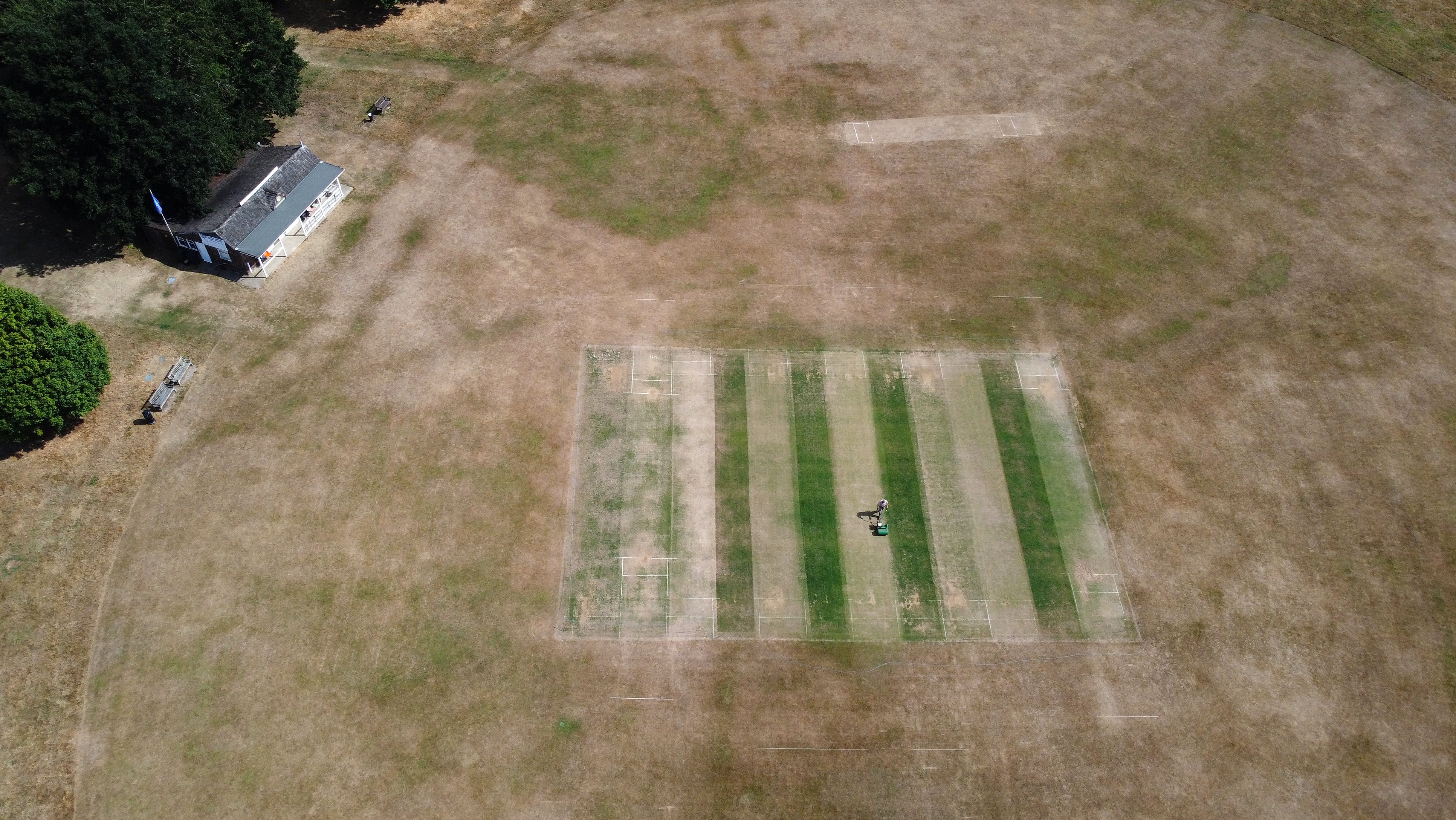 Vic Lilley, groundsman at Boughton and Eastwell Cricket Club in Ashford, Kent, prepares the wickets on a parched cricket pitch (Gareth Fuller/PA)