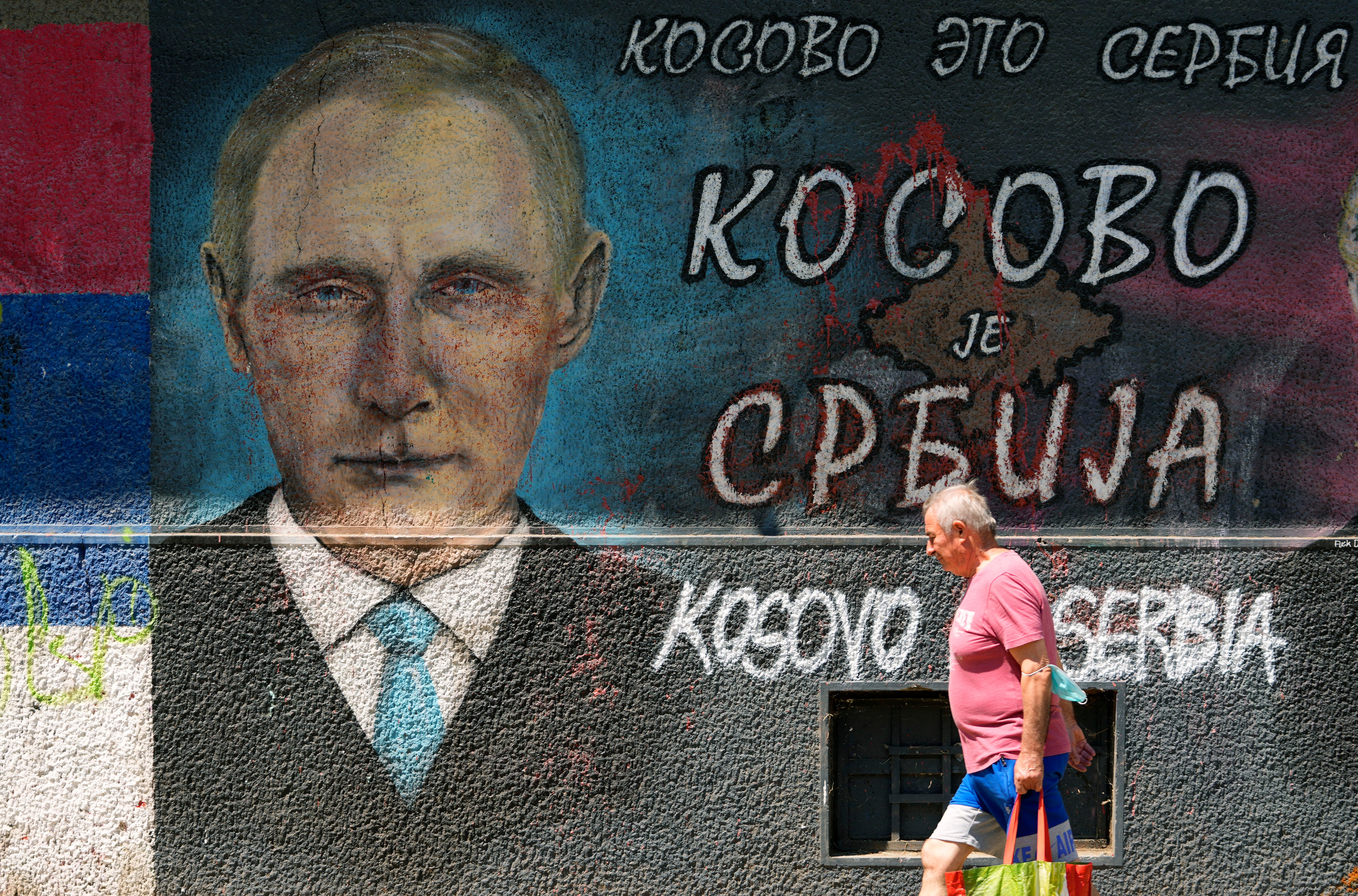 A man passes by graffiti depicting Russian President Vladimir Putin, reading: ‘Kosovo is Serbia’ in Belgrade