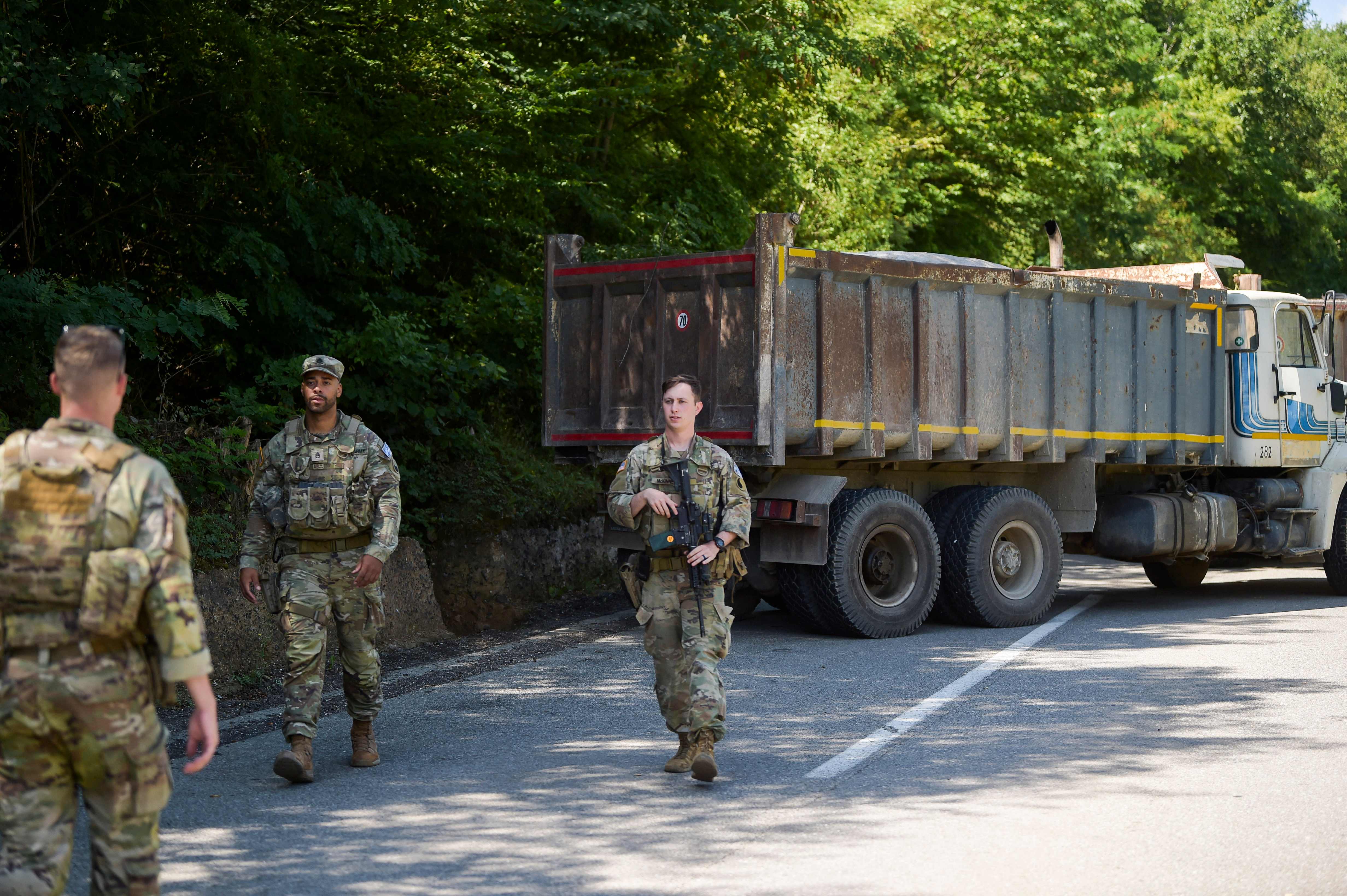 US Nato soldiers serving in Kosovo patrol next to a road barricade set up by ethnic Serbs near the town of Zubin Potok