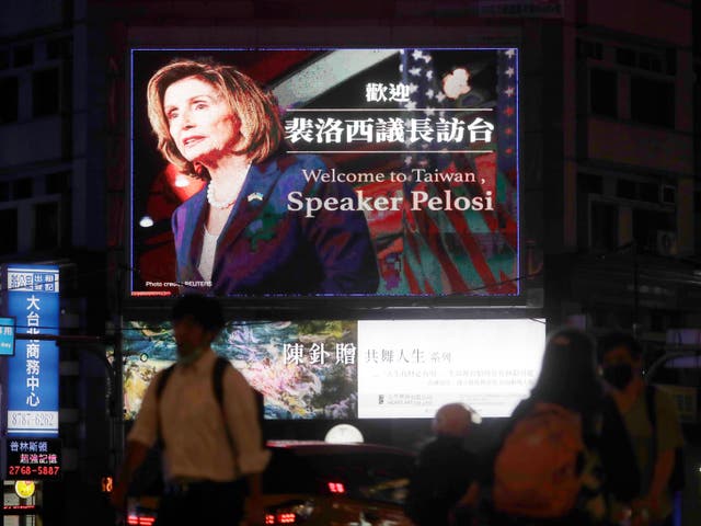 La gente pasa frente a un cartel que da la bienvenida a la presidenta de la Cámara de Representantes de los Estados Unidos, Nancy Pelosi, en Taipei, Taiwán, el martes 2 de agosto de 2022.