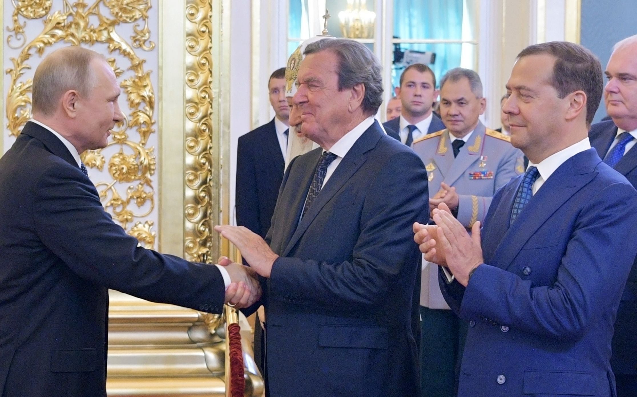 n this file photo taken on May 7, 2018 Russian president-elect Vladimir Putin shakes hands with former German Chancellor Gerhard Schroeder as Dmitry Medvedev stands nearby