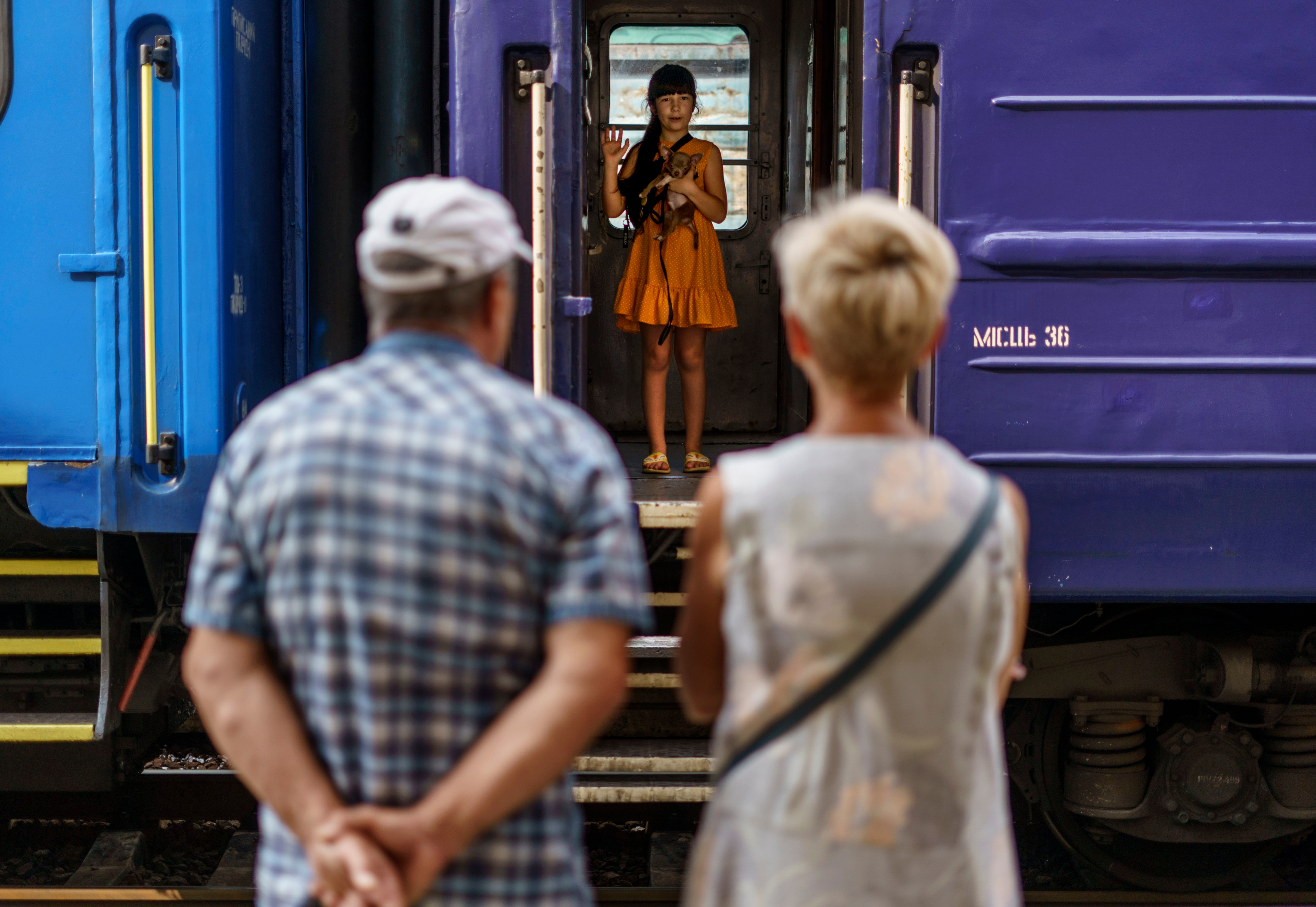 File: A young girl holds her dog while waving goodbye to her grandparents from a train departing Pokrovsk, Donetsk region, eastern Ukraine