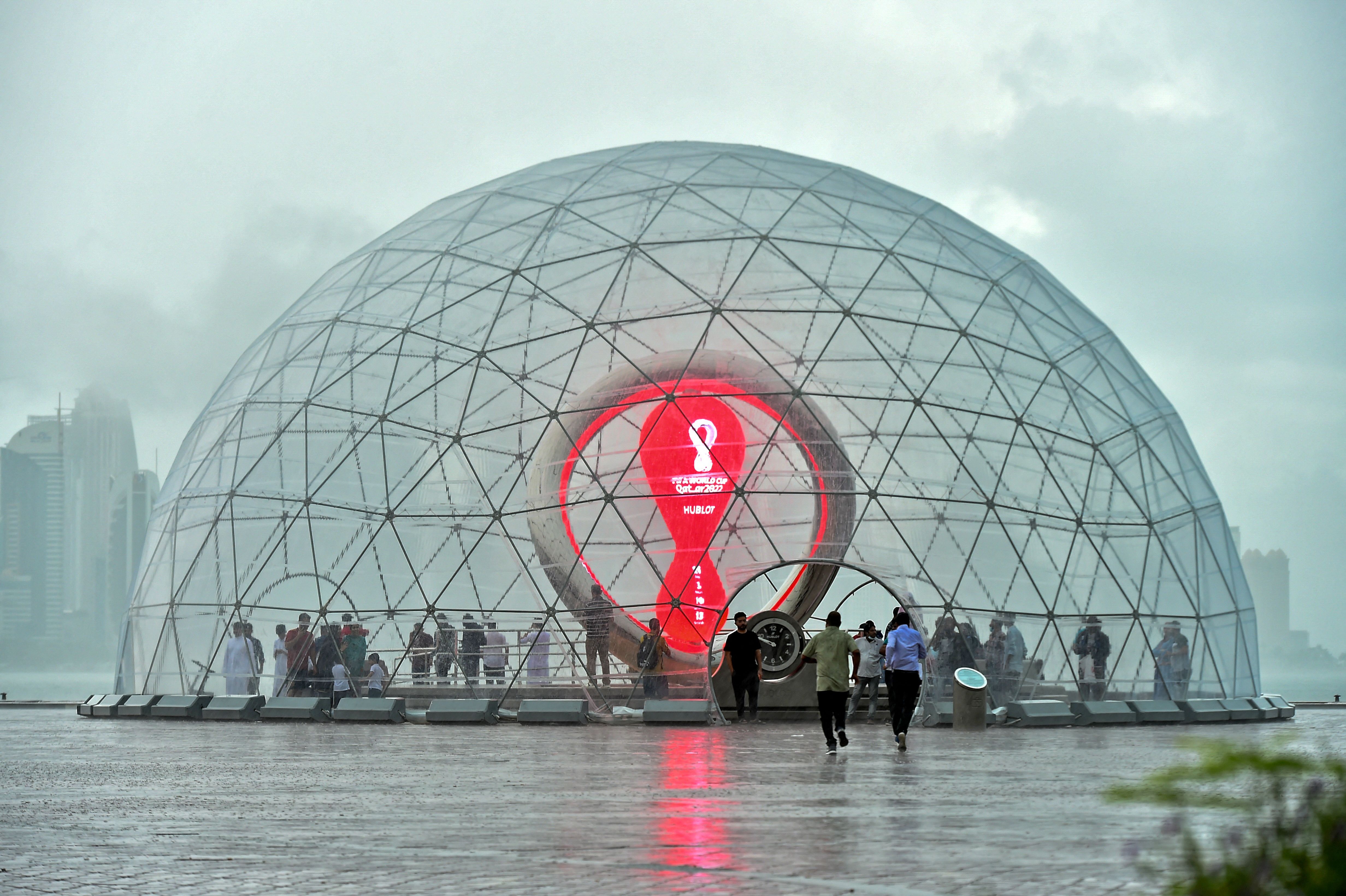 <p>People take cover inside the FIFA World Cup Qatar 2022 countdown clock during heavy rains in the Qatari capital Doha on July 28</p>