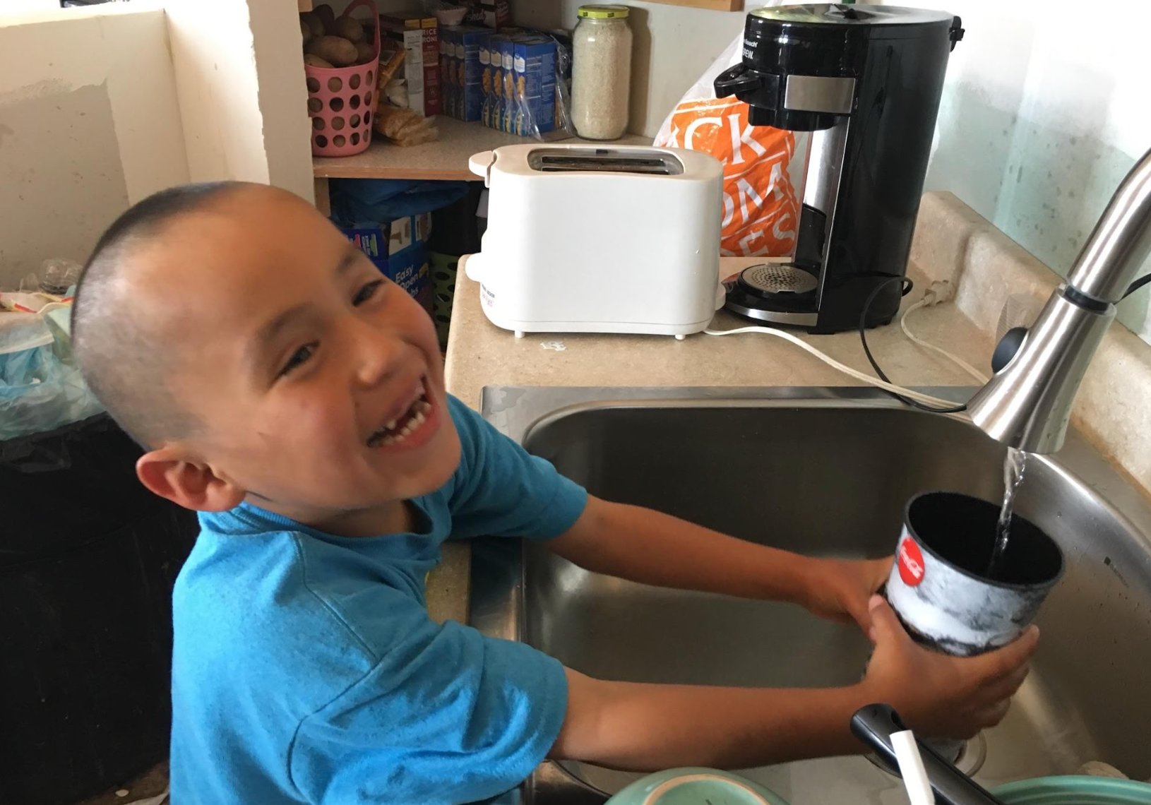 A young boy gets a glass of water after having running water installed by the Navajo Water Project