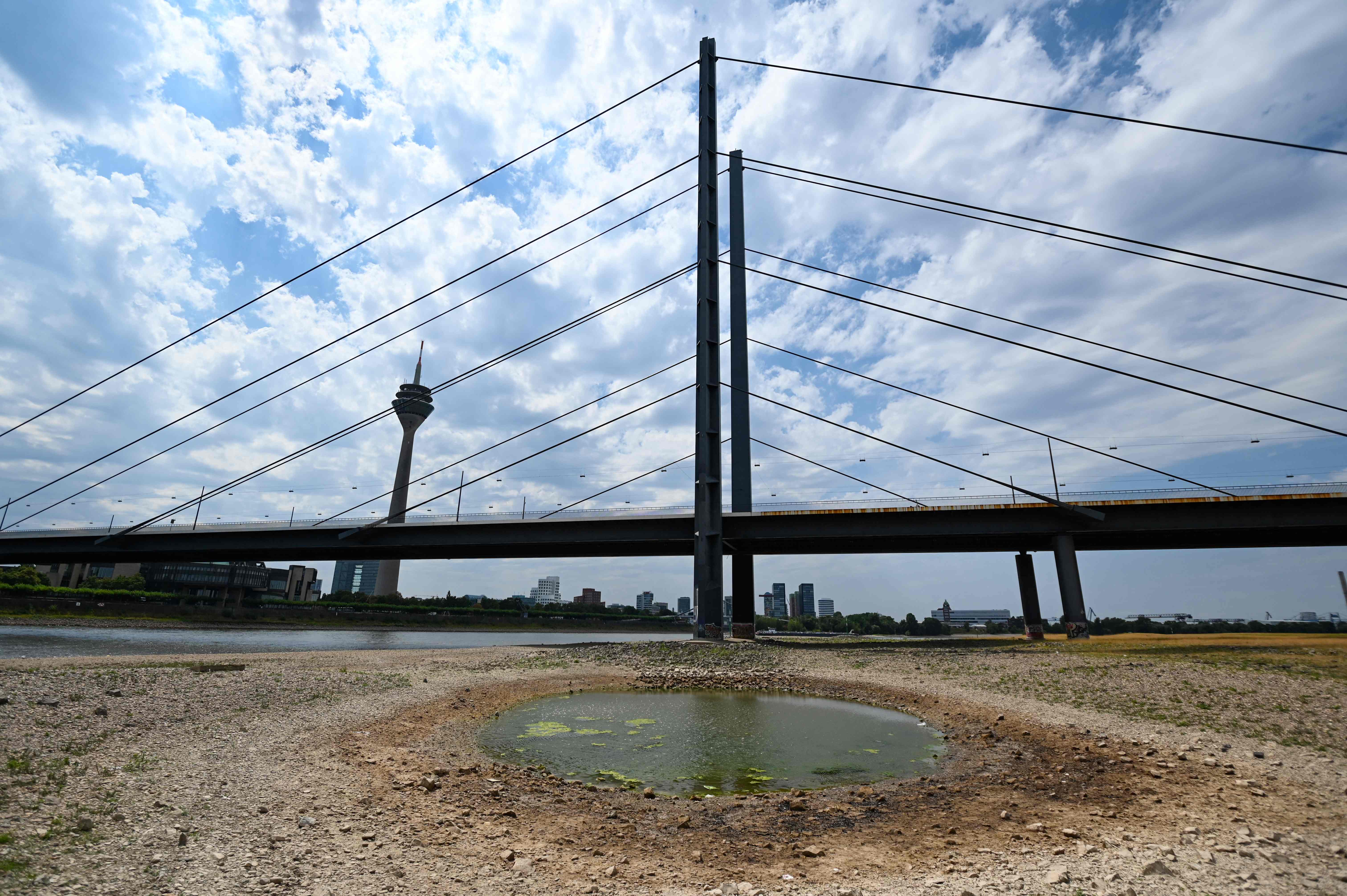 An inland vessel navigates on the Rhine as the partially dried-up river bed is seen in the foreground in Duesseldorf, western Germany, in July 2022