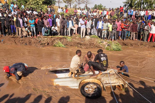 <p>People work to retrieve flood victims out of a minibus in Uganda on Monday</p>