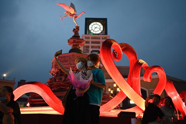<p>A couple pose for photographs at a shopping mall during the Qixi Festival in Beijing </p>