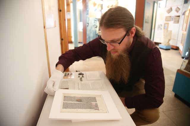 A curator at Glastonbury Abbey handling the 800-year-old page (Glastonbury Abbey/PA)