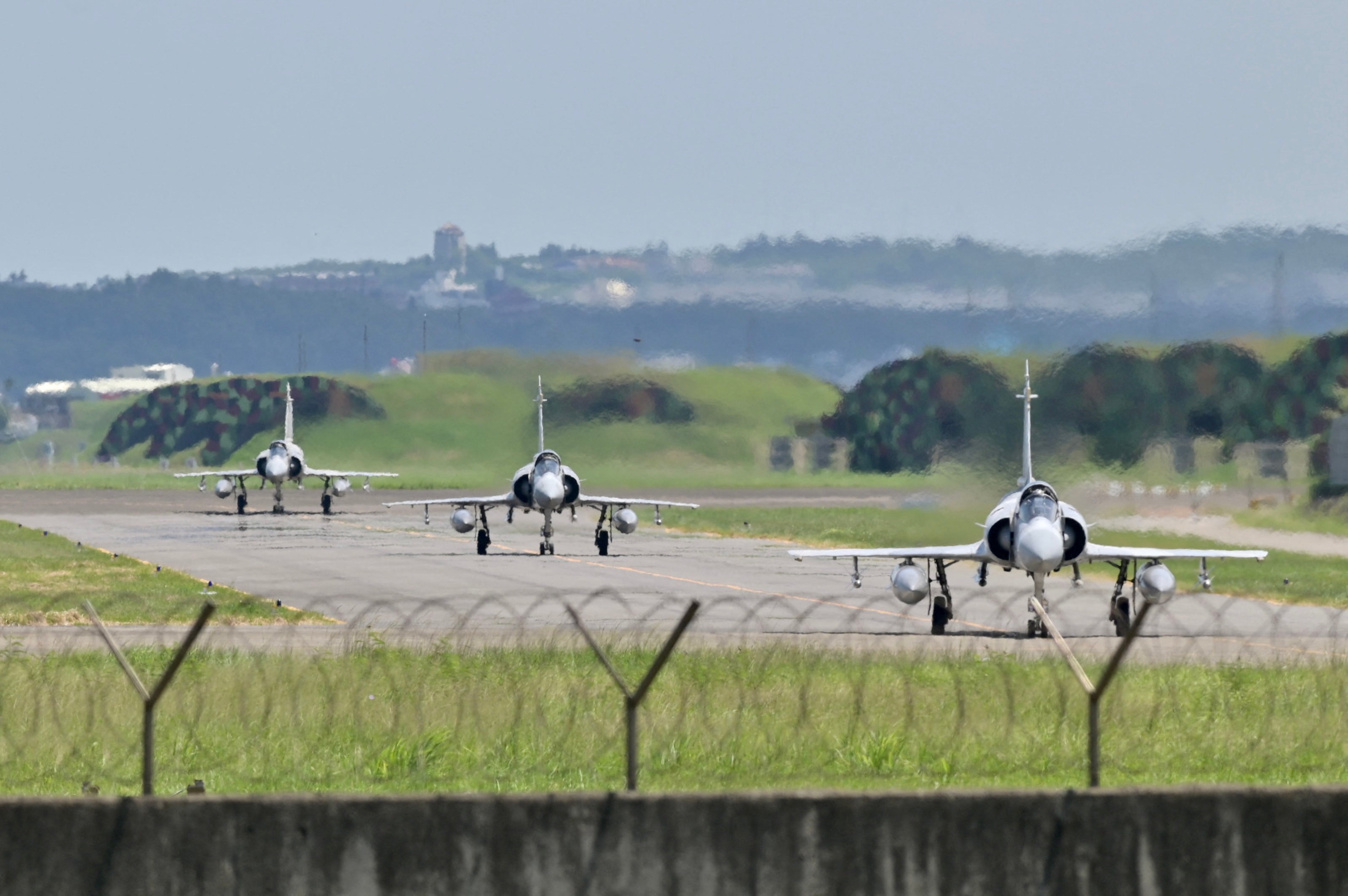 Three French-made Mirage 2000 fighter jets taxi on a runway in front of a hangar at the Hsinchu Air Base in Hsinchu on 5 August 2022