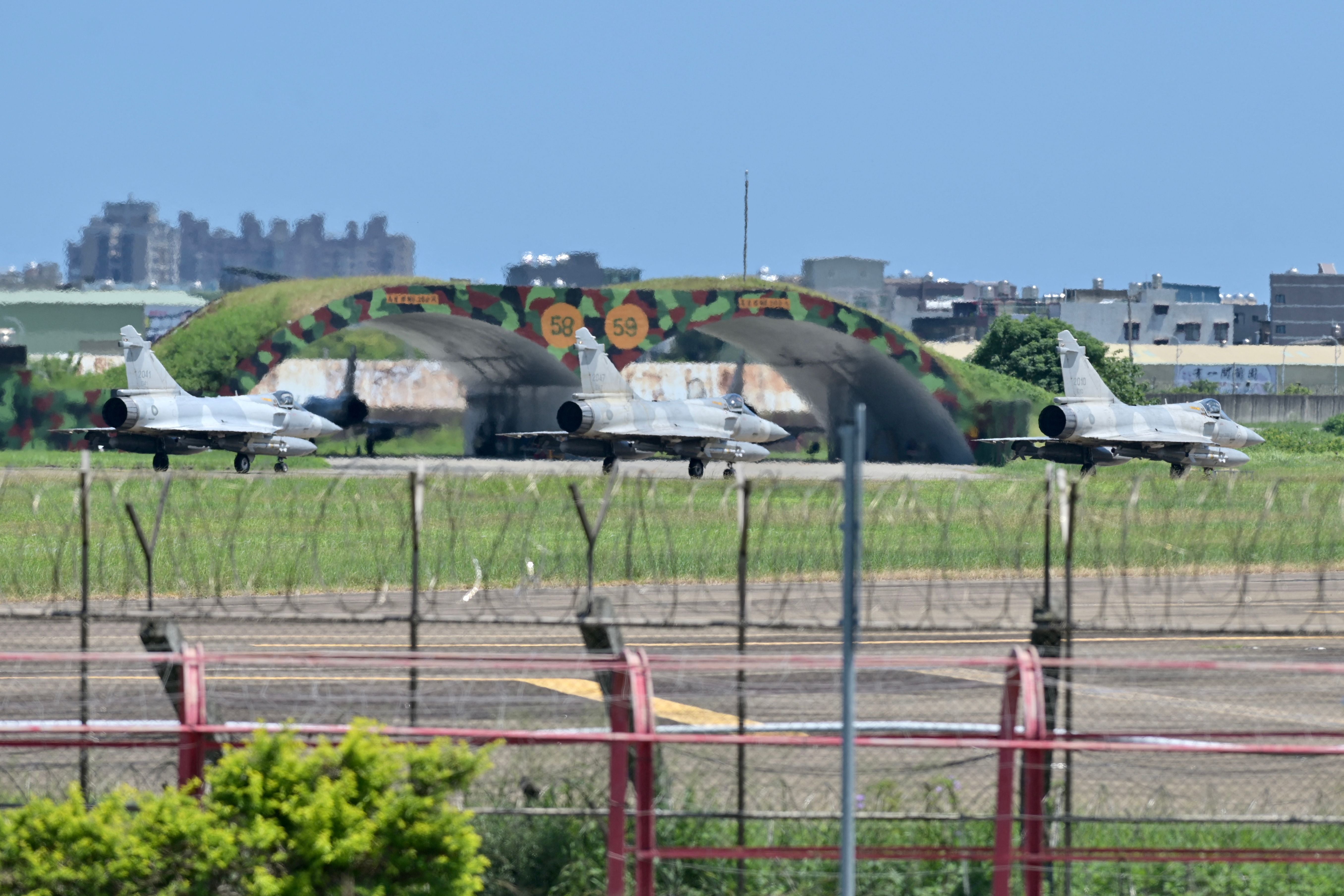 Three French-made Mirage 2000 fighter jets taxi on a runway in front of a hangar at the Hsinchu Air Base in Hsinchu on 5 August 2022