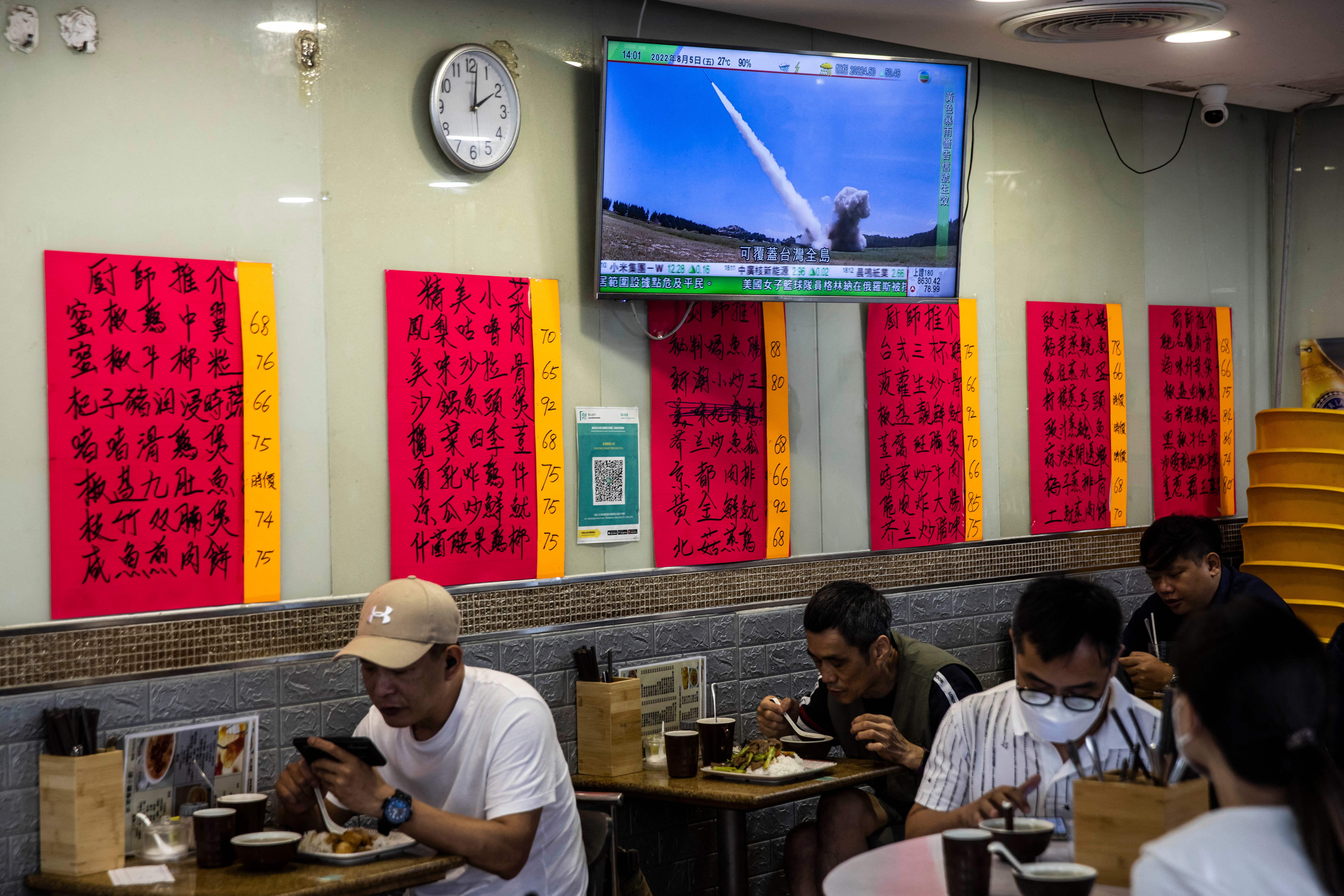 A television (top) in a restaurant in Hong Kong on 5 August 2022, shows a missile being launched during military exercises being held by China around the island of Taiwan