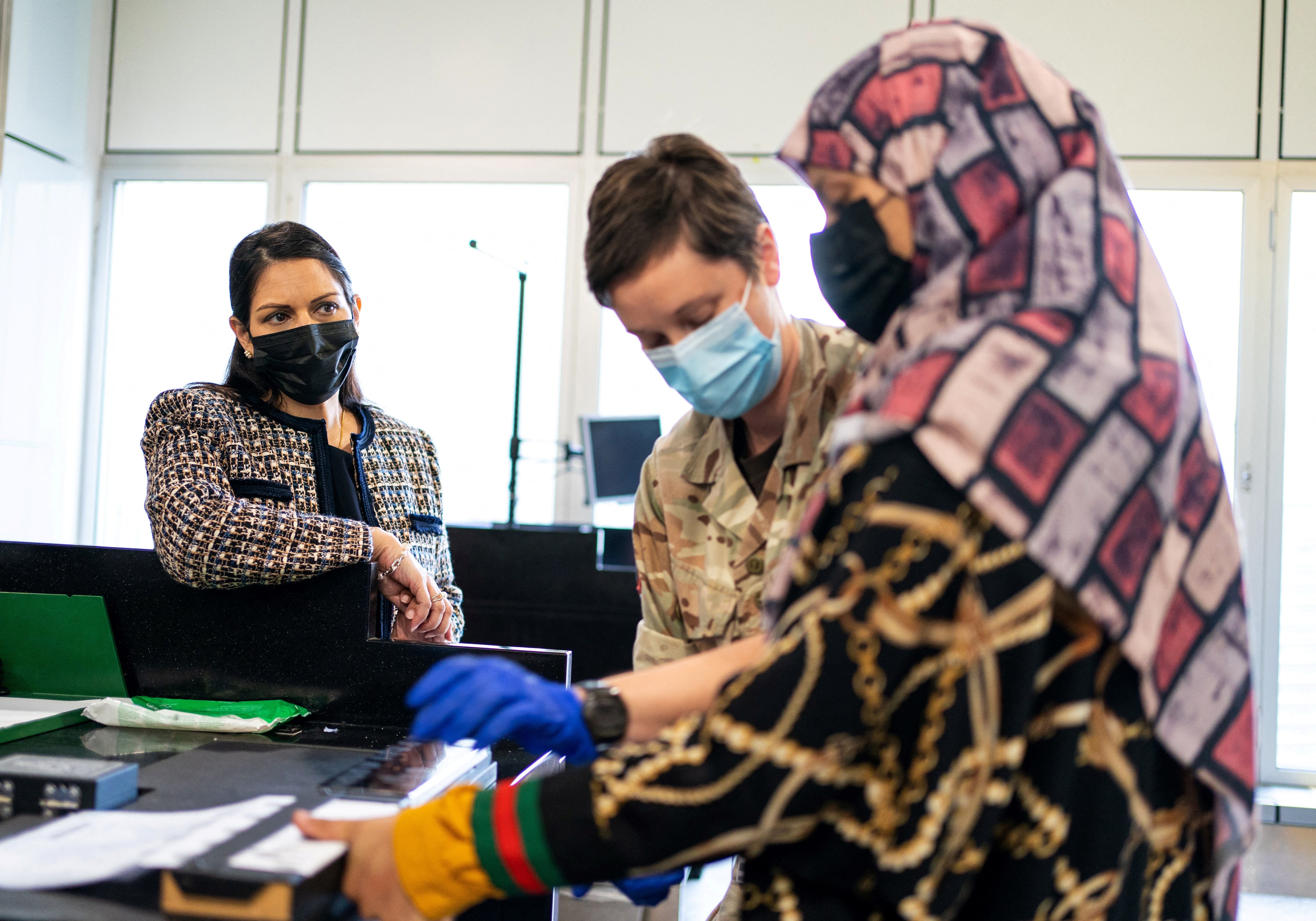 Britain's Home Secretary Priti Patel watches as an Afghan refugee has her fingerprints taken on her arrival