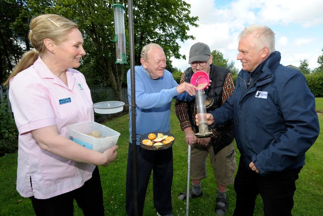 (l-r) Julie-Ann McStravick, care home residents Bob Richardson and David Duprey and Peter Harper of the Lough Neagh Partnership fill one of the bird feeders(Edward Byrne/PA)