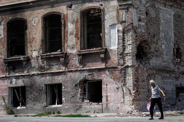 <p>A woman walks past a destroyed building in Mariupol, Ukraine, on 1 August, 2022. </p>
