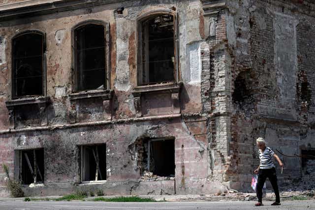 <p>A woman walks past a destroyed building in Mariupol, Ukraine, on 1 August, 2022. </p>