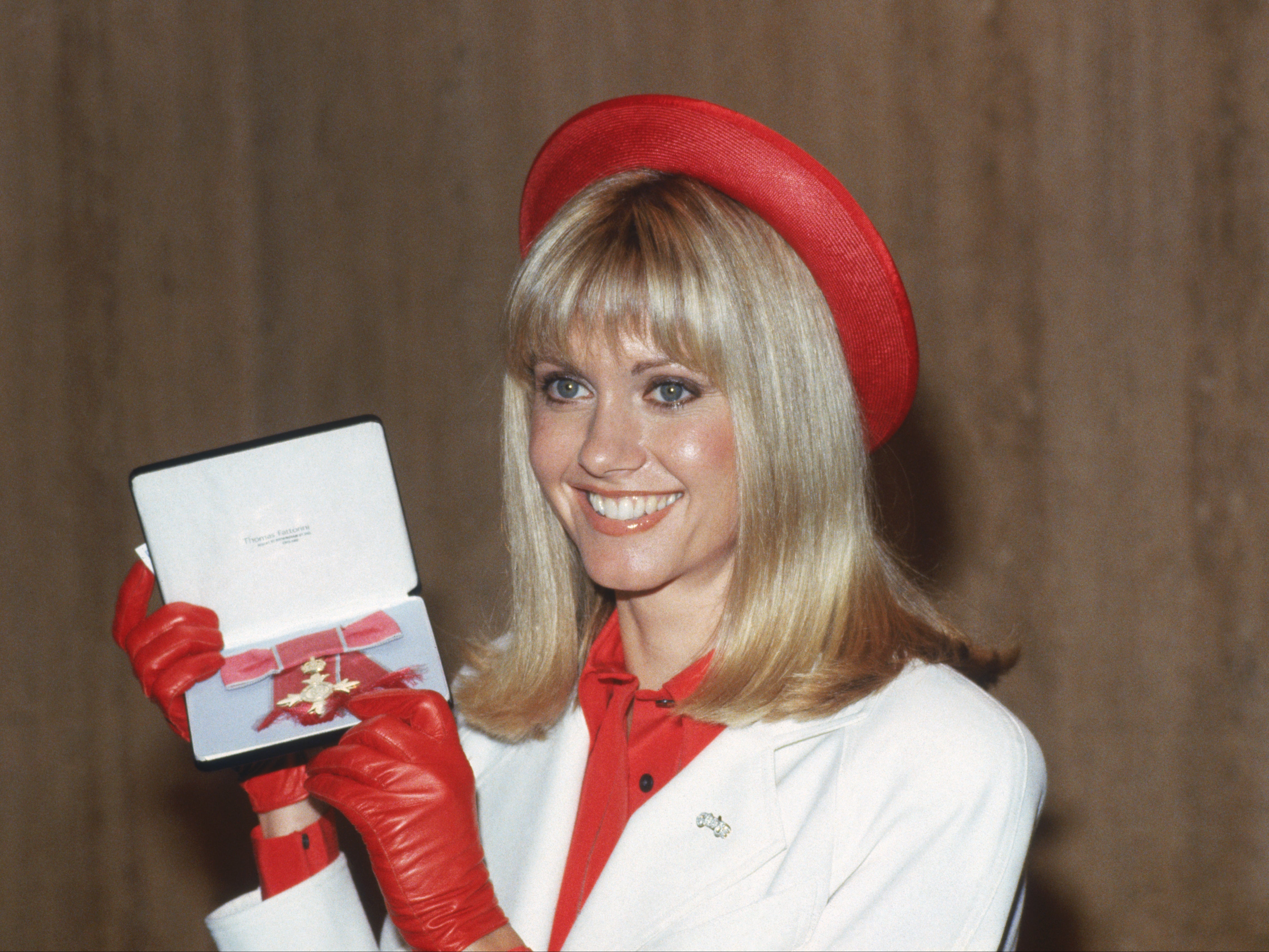Newton-John receiving an OBE at Buckingham Palace in 1979. She was later made a Dame in 2020 for services to charity, cancer research and entertainment