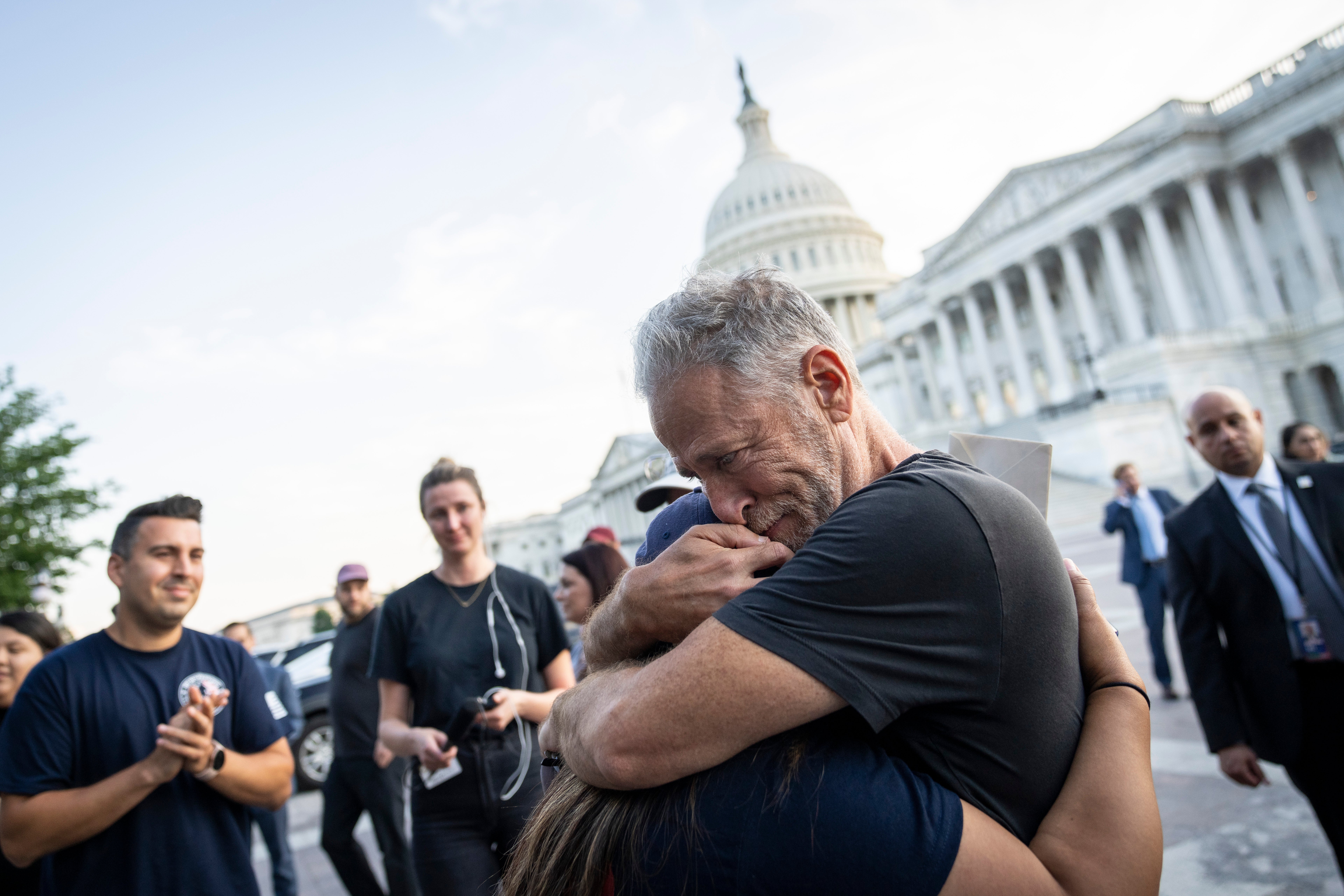 Jon Stewart hugs Rosie Torres, wife of veteran Le Roy Torres who suffers from illnesses related to his exposure to burn pits in Iraq, after the Senate passed the PACT Act on 2 August