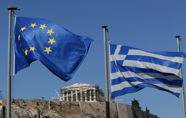 <p>The Greek, right, and the European flags wave under the ancient Acropolis hill in Athens</p>