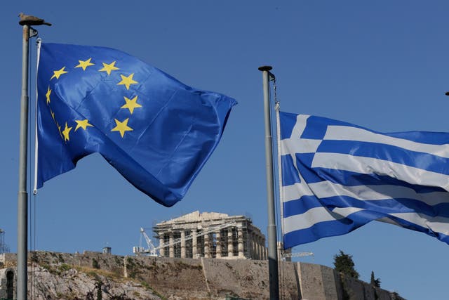 <p>The Greek, right, and the European flags wave under the ancient Acropolis hill in Athens</p>