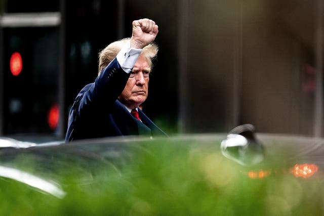 <p>Donald Trump raises his fist as he departs Trump Tower in New York City on his way to testify before the state attorney general</p>