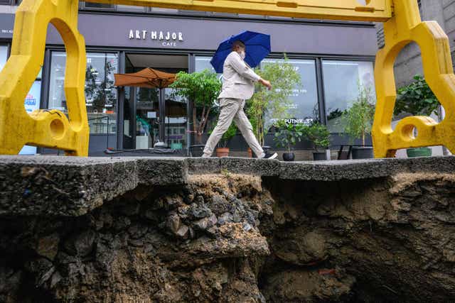 <p>A man walks past a damaged pavement in Seoul on 9 August after record-breaking rains caused severe flooding</p>