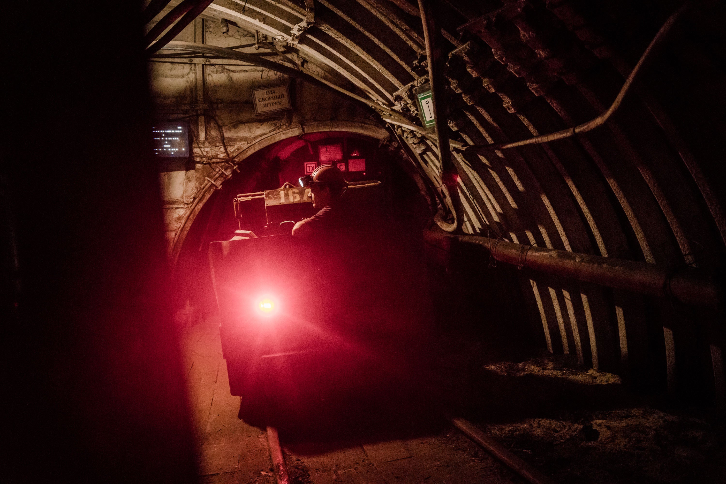 Coal miners travel by rail through miles of underground tunnels during their shift