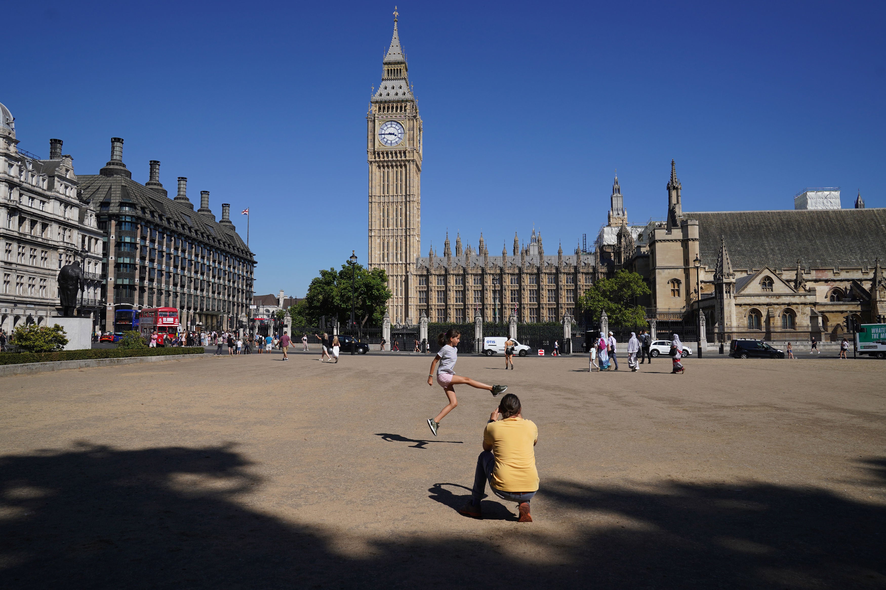 People on the dead grass in Parliament Square Garden, Westminster, central London