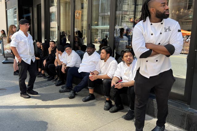 <p>Kitchen staff wait outside a restaurant during an electricity outage in Toronto, Canada, on Aug 11 2022</p>