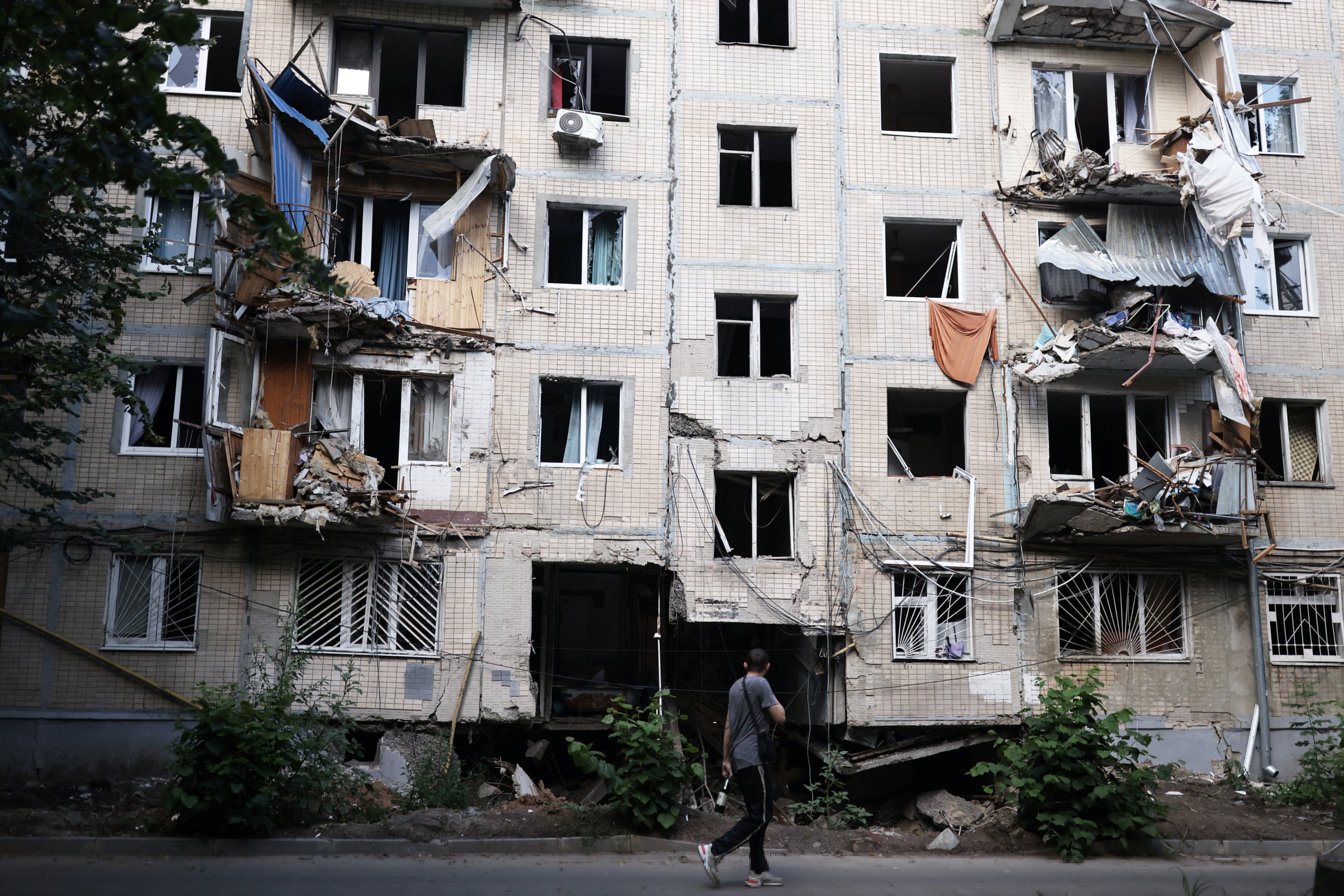 A man walks past a destroyed building next to Maria’s house after a military strike