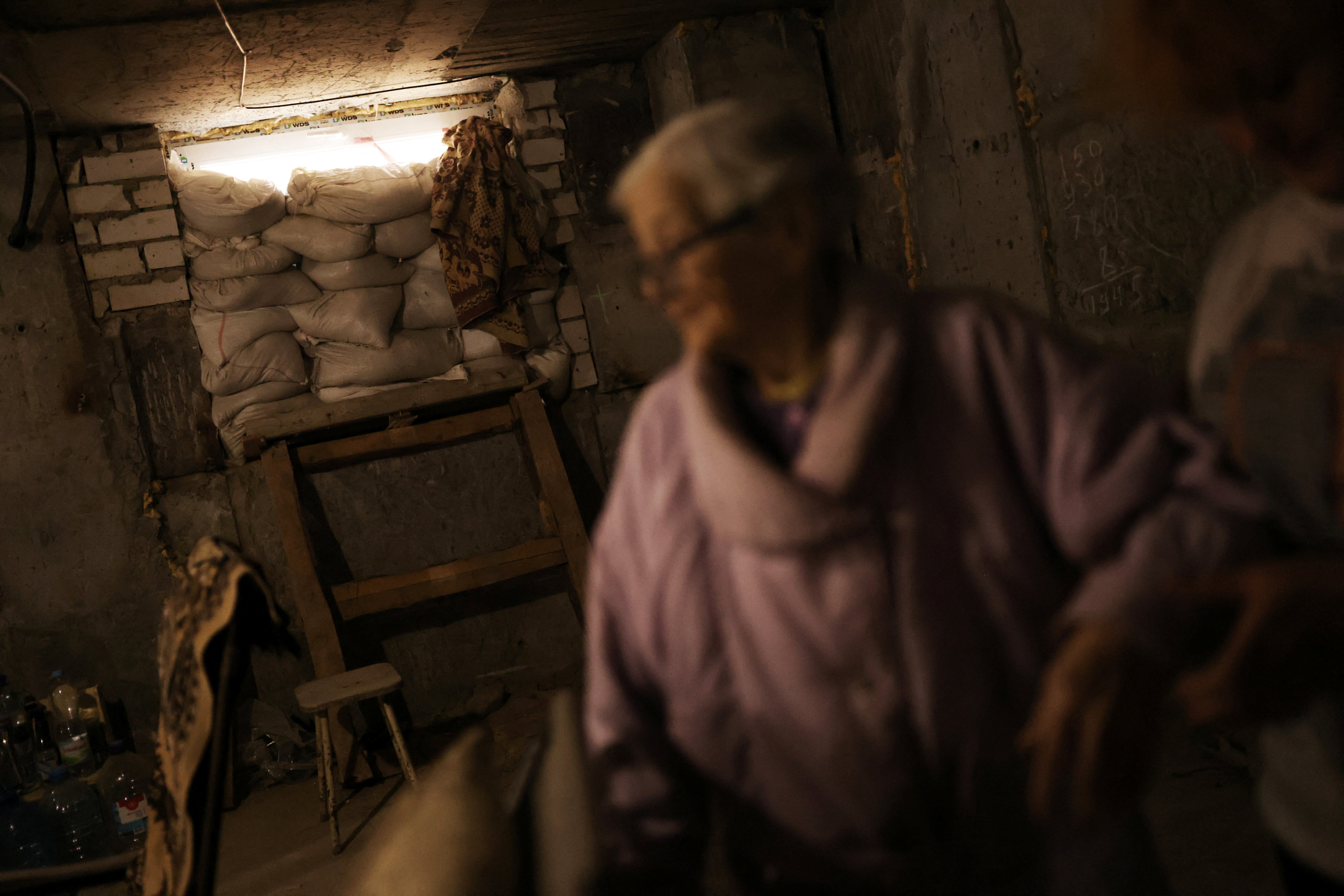 Maria walks with the help of her daughter, in front of protective sandbags