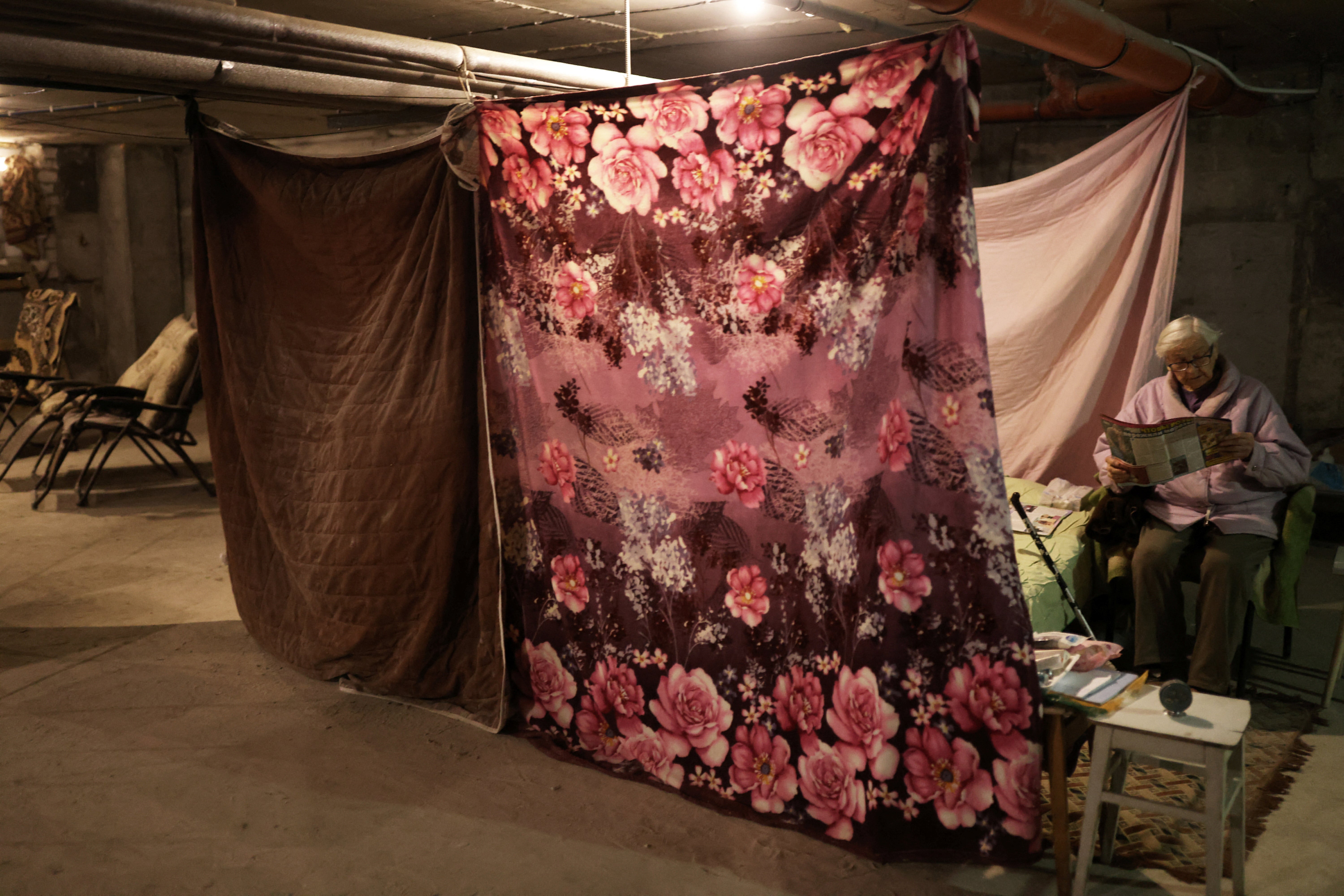 Maria reads a magazine in front of a makeshift bedroom