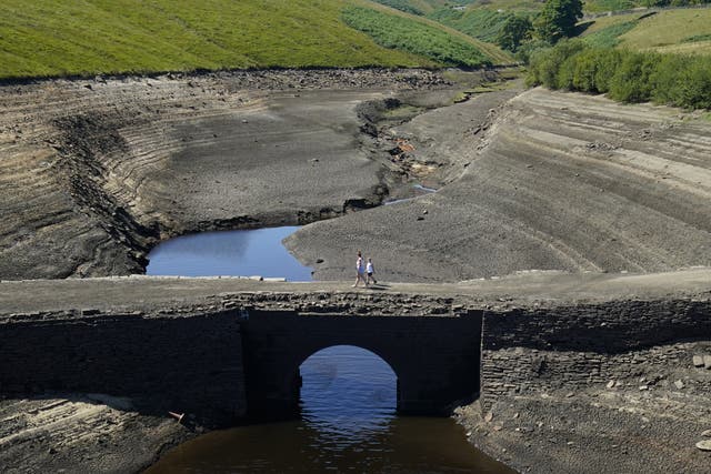 People walk across a previously submerged bridge at Baitings reservoir in Ripponden, West Yorkshire (Danny Lawson/PA)