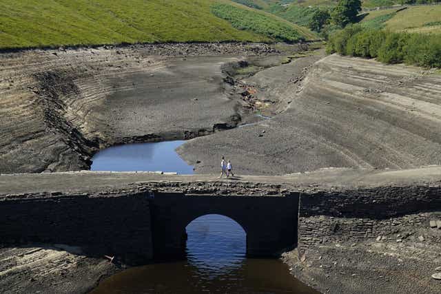 People walk across a previously submerged bridge at Baitings reservoir in Ripponden, West Yorkshire (Danny Lawson/PA)