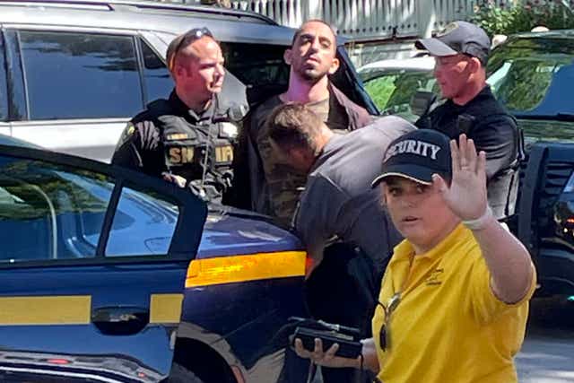 <p>Law enforcement officers detain Hadi Matar, 24, of Fairview, N.J., outside the Chautauqua Institution, Friday, Aug. 12, 2022, in Chautauqua, N.Y.. Salman Rushdie, the author whose writing led to death threats from Iran in the 1980s, was attacked and apparently stabbed in the neck Friday by Matar who rushed the stage as he was about to give a lecture at the institute in western New York</p>