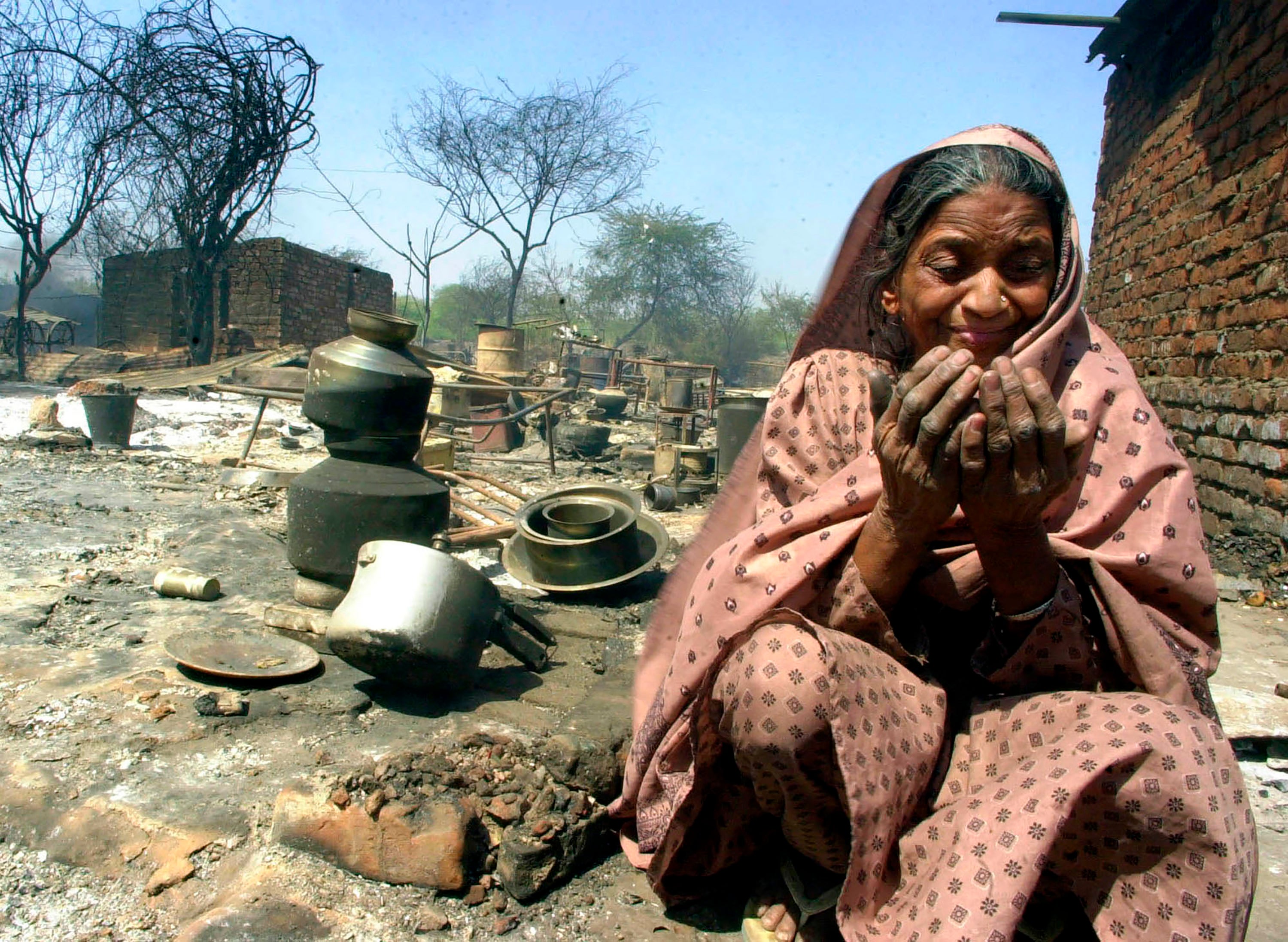 Razia, a Muslim woman, cries while praying by her destroyed home near Ahmedabad, India, March 2, 2002