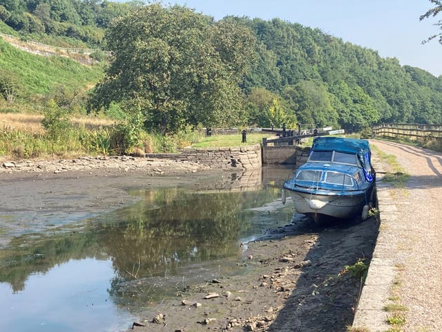A boat lies in the dried up Huddersfield narrow canal near Linthwaite (Ashley Broadley/PA)